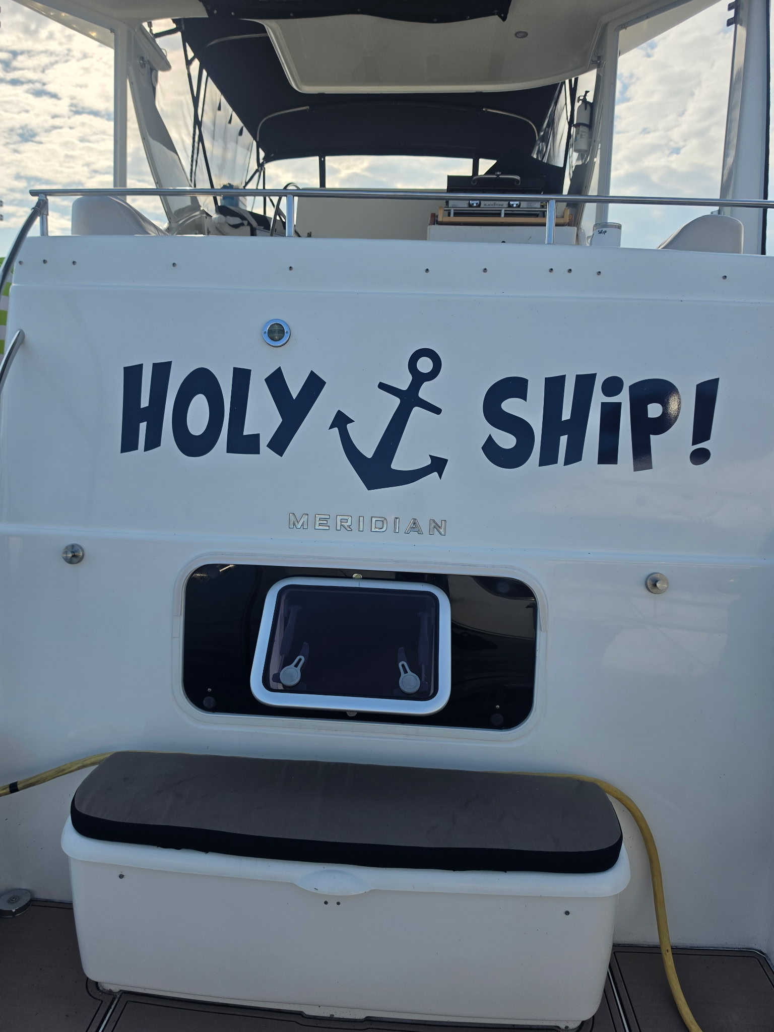 Holy Ship's transom before — the old flat navy vinyl name on weathered gelcoat