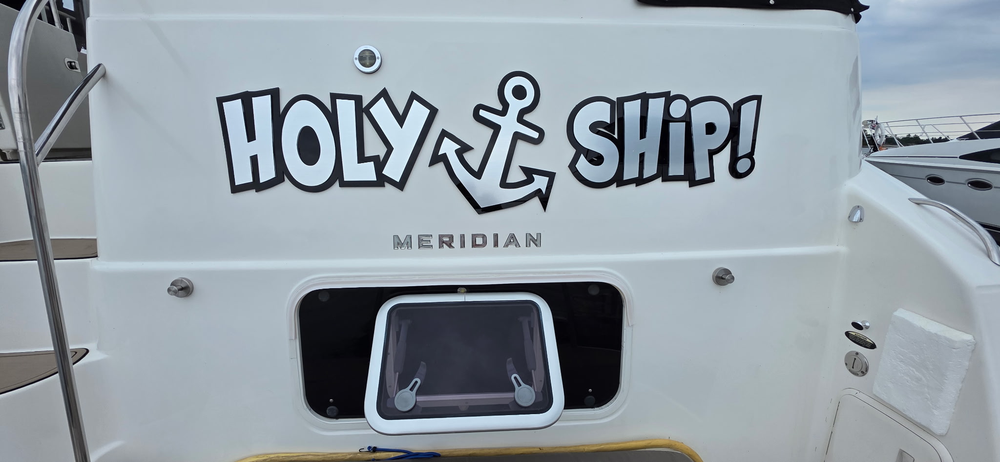 Holy Ship's transom with the name in dimensional mirror-chrome cast acrylic over a glossy white hull